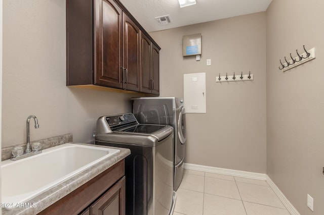 washroom with cabinets, a textured ceiling, sink, light tile patterned floors, and independent washer and dryer