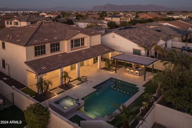 pool at dusk featuring a patio area and an in ground hot tub