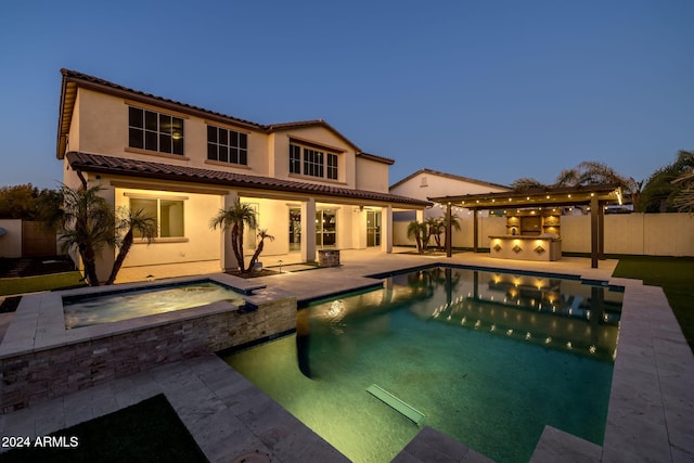 pool at dusk featuring an in ground hot tub and a patio area