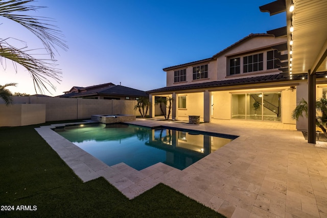 pool at dusk featuring an in ground hot tub and a patio area