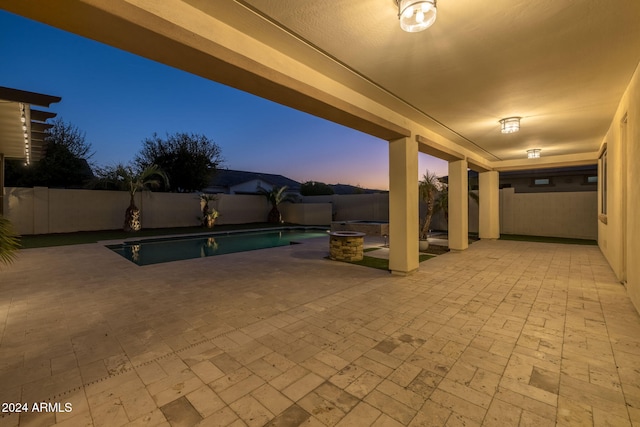 patio terrace at dusk with a swimming pool with hot tub