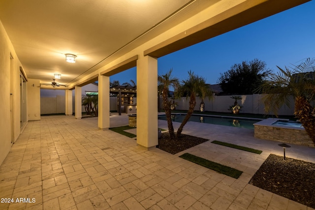 patio terrace at dusk with ceiling fan and a swimming pool with hot tub