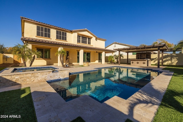 back of house featuring a swimming pool with hot tub, an outdoor kitchen, and a patio