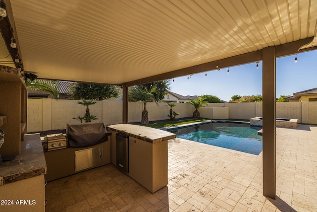 view of swimming pool with grilling area, a patio, and exterior kitchen