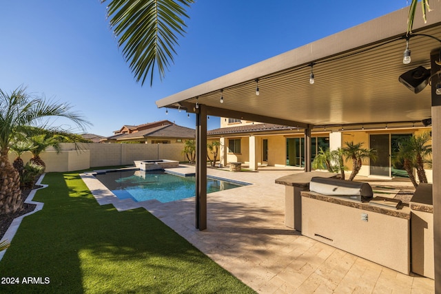 view of pool with a lawn, a patio area, and exterior kitchen