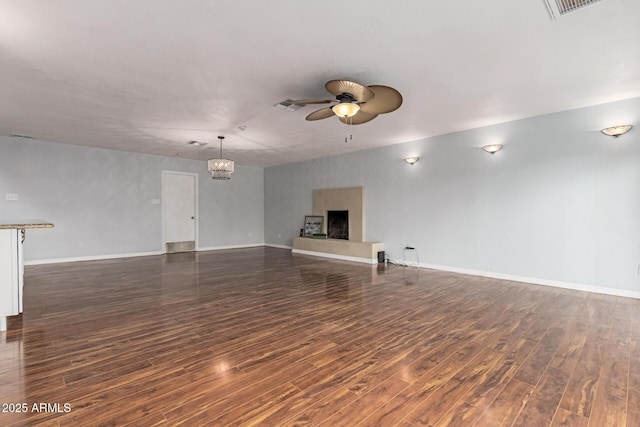 100 E Geneva Dr, Tempe, AZ 85282 - unfurnished living room featuring ceiling fan, dark wood finished floors, a chandelier, baseboards, and a fireplace with raised hearth