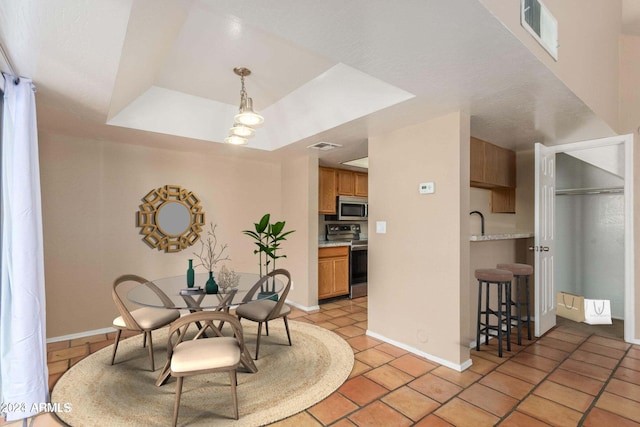 tiled dining room with a tray ceiling and sink