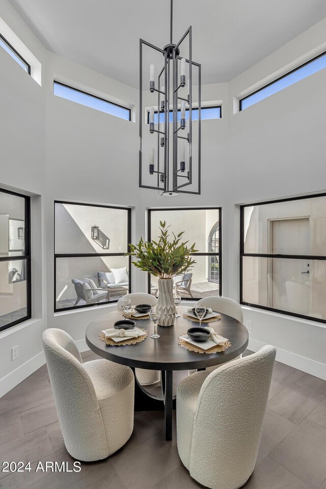 3800 E Lincoln Dr Unit 42, Phoenix, AZ 85018 - dining space featuring a high ceiling, a chandelier, plenty of natural light, baseboards, and wood finished floors
