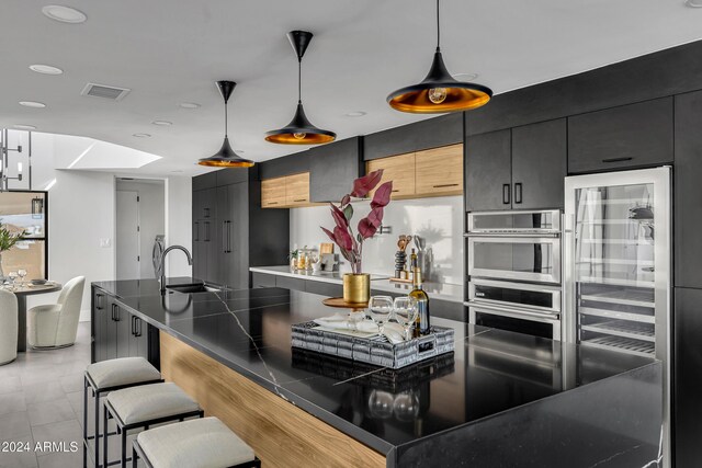 3800 E Lincoln Dr Unit 42, Phoenix, AZ 85018 - kitchen with stainless steel double oven, dark cabinets, a kitchen bar, a sink, and wine cooler