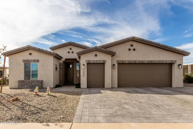 mediterranean / spanish home featuring a garage, decorative driveway, a tile roof, and stucco siding