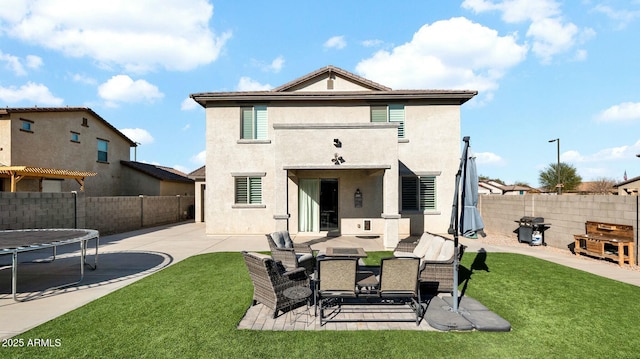 back of house with a yard, a trampoline, and a patio area