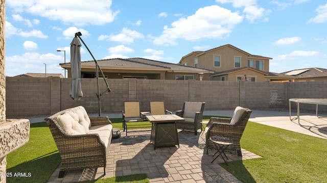 view of patio with a trampoline and an outdoor living space with a fire pit