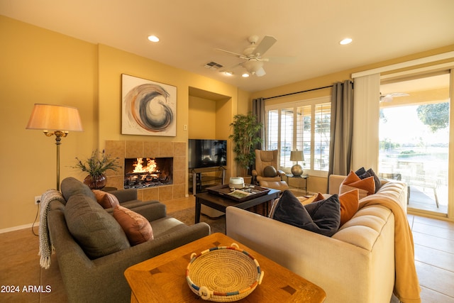 living room with a tiled fireplace, tile patterned flooring, and ceiling fan