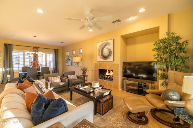 living room with a tile fireplace and ceiling fan with notable chandelier