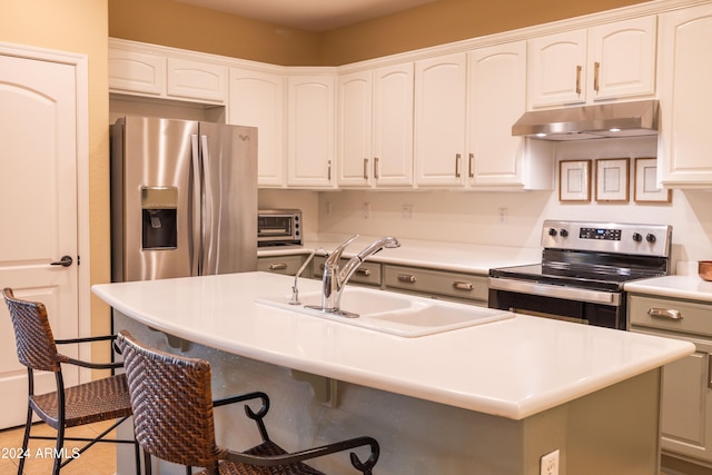 kitchen featuring a kitchen breakfast bar, a center island with sink, sink, white cabinetry, and appliances with stainless steel finishes