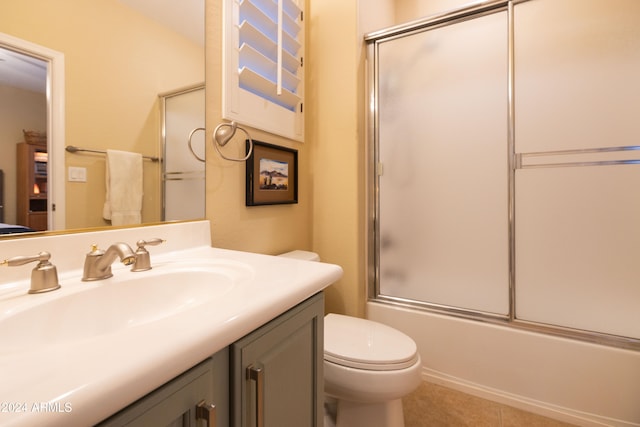 full bathroom featuring vanity, shower / bath combination with glass door, toilet, and tile patterned flooring