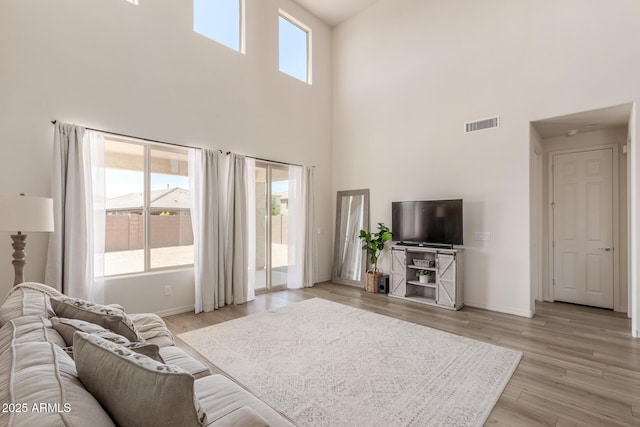 living room featuring light hardwood / wood-style floors and a towering ceiling