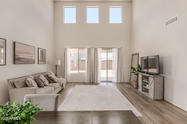 living room featuring a high ceiling and light hardwood / wood-style flooring