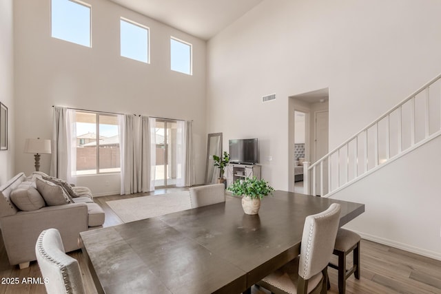 dining area featuring a towering ceiling and light hardwood / wood-style floors