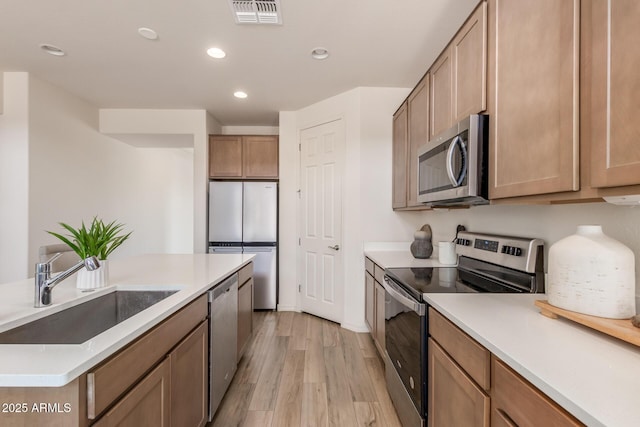 kitchen with sink, light hardwood / wood-style floors, and appliances with stainless steel finishes