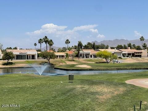 view of property's community with a lawn, view of golf course, and a water and mountain view