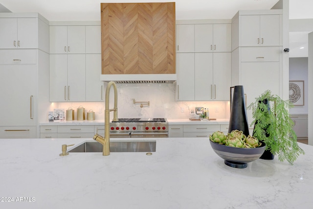 kitchen featuring white cabinetry, light stone countertops, and tasteful backsplash