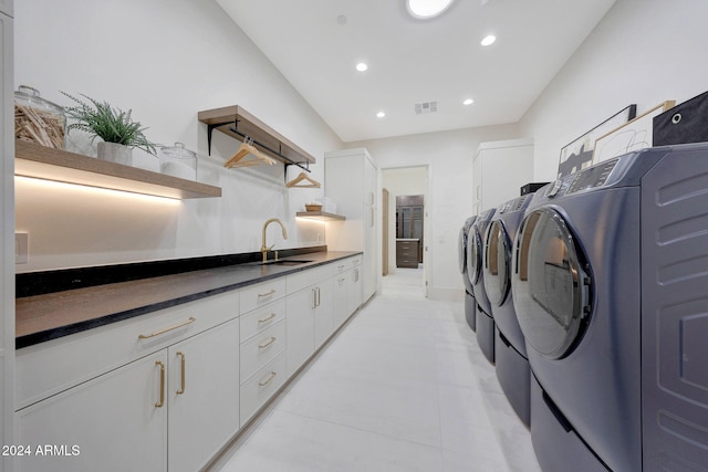 laundry room featuring cabinets, light tile patterned flooring, sink, and washing machine and clothes dryer