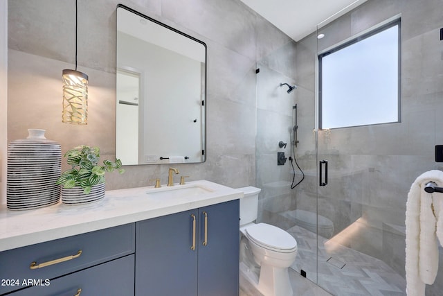 bathroom featuring tile walls, vanity, a shower with shower door, and toilet