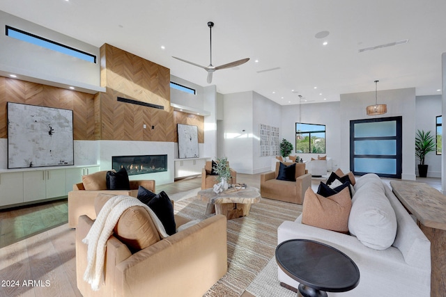 living room with light hardwood / wood-style floors, a large fireplace, and ceiling fan