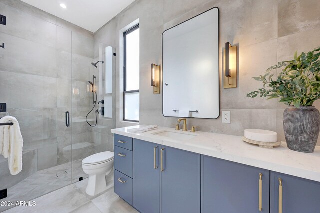 bathroom featuring vanity, toilet, tile walls, and a shower with door