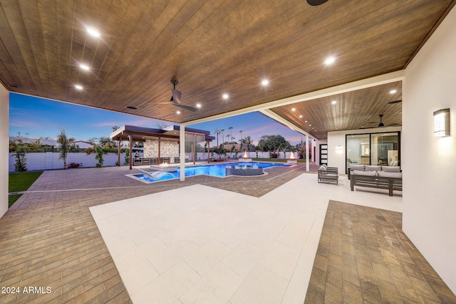 pool at dusk with ceiling fan, a patio area, and outdoor lounge area