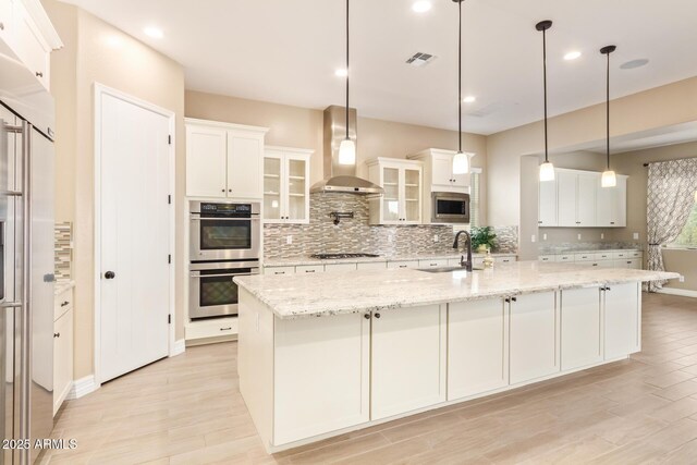 kitchen featuring appliances with stainless steel finishes, sink, wall chimney exhaust hood, and white cabinetry