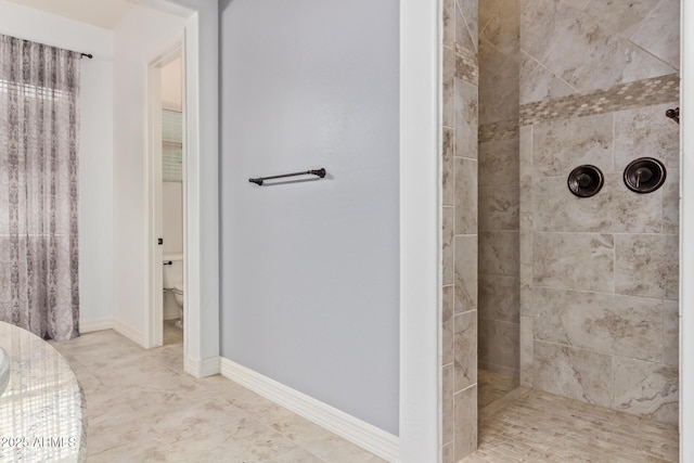 bathroom with a tile shower and toilet