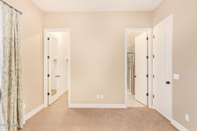 interior space featuring ensuite bath and light colored carpet