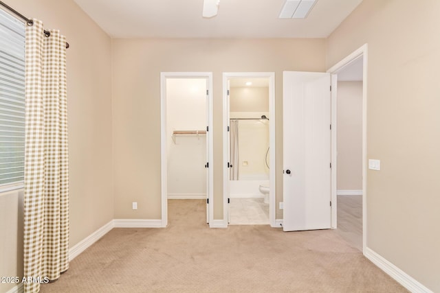 unfurnished bedroom with a closet, light carpet, connected bathroom, and a spacious closet