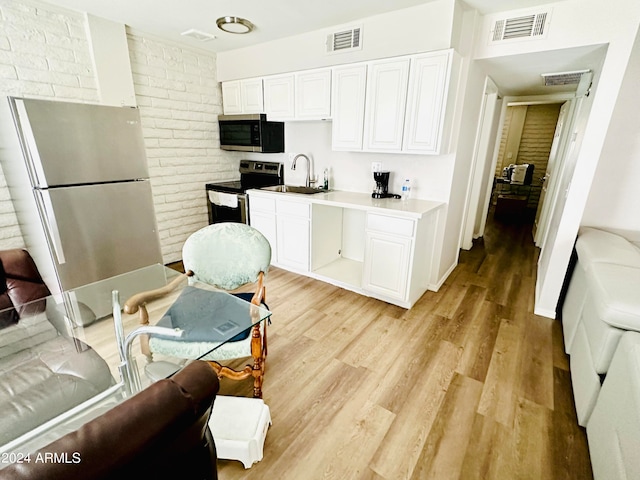 kitchen featuring white cabinets, light hardwood / wood-style flooring, stainless steel appliances, brick wall, and sink