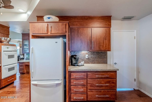 kitchen with ceiling fan, light wood-type flooring, backsplash, and white appliances