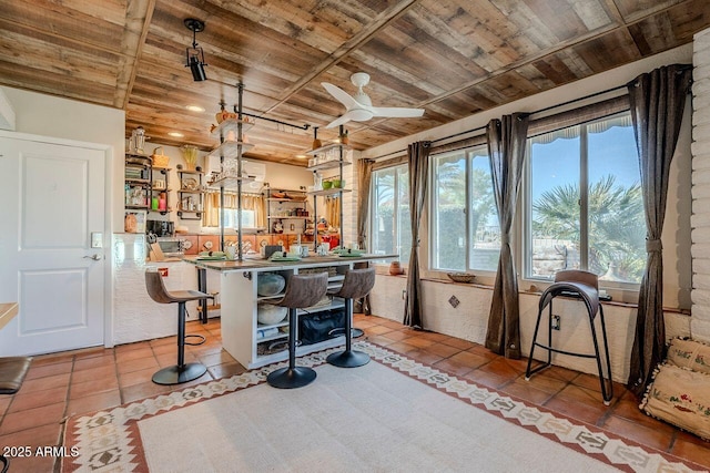 kitchen with light tile patterned floors, a breakfast bar area, wooden ceiling, and kitchen peninsula