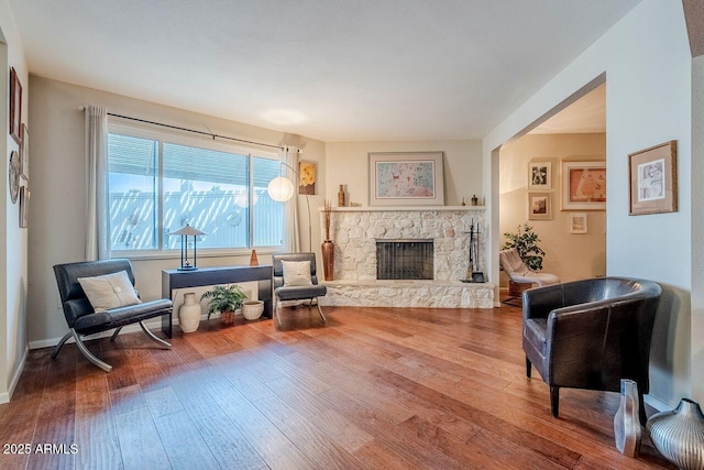 sitting room with hardwood / wood-style flooring and a stone fireplace