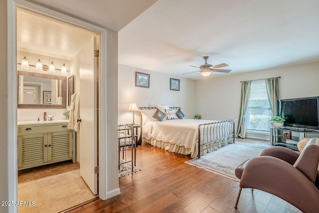 bedroom featuring ensuite bath, light hardwood / wood-style floors, and ceiling fan