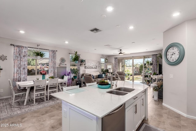 kitchen featuring sink, white cabinetry, light stone counters, stainless steel dishwasher, and an island with sink