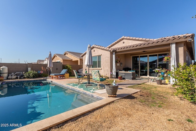 back of property with a fenced in pool and a patio