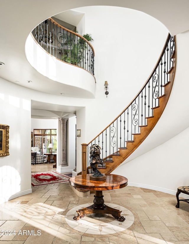 entryway featuring a towering ceiling and decorative columns