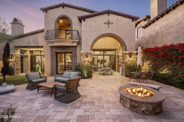 patio terrace at dusk with a balcony and an outdoor living space with a fire pit