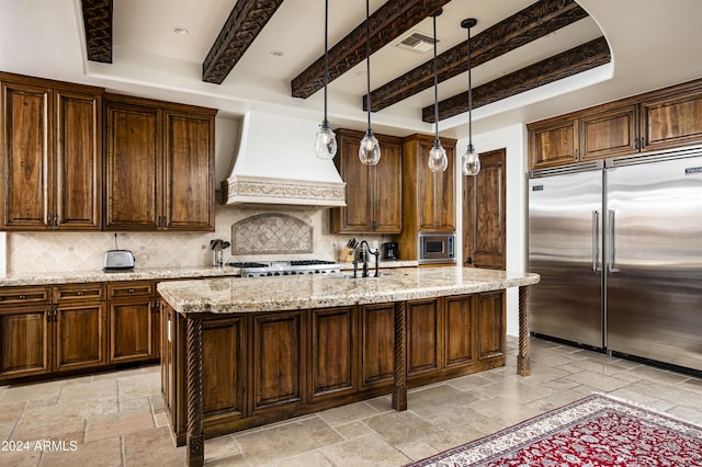 kitchen featuring tasteful backsplash, built in appliances, an island with sink, and custom exhaust hood