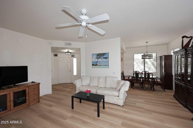 living room with light wood-type flooring, ceiling fan, and visible vents