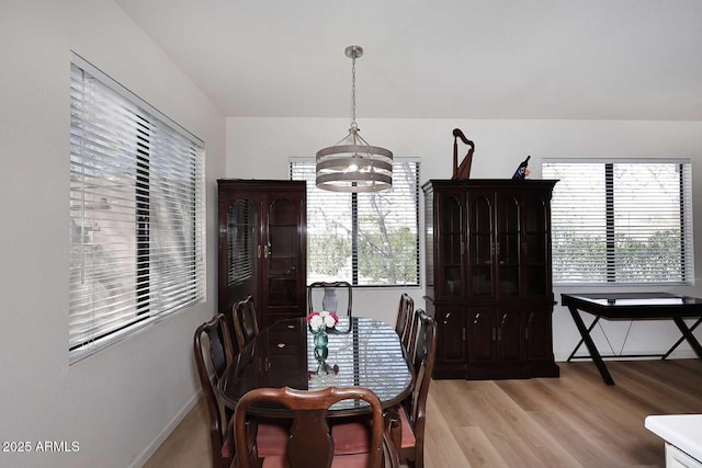 dining space with light wood-style floors, a wealth of natural light, a notable chandelier, and baseboards