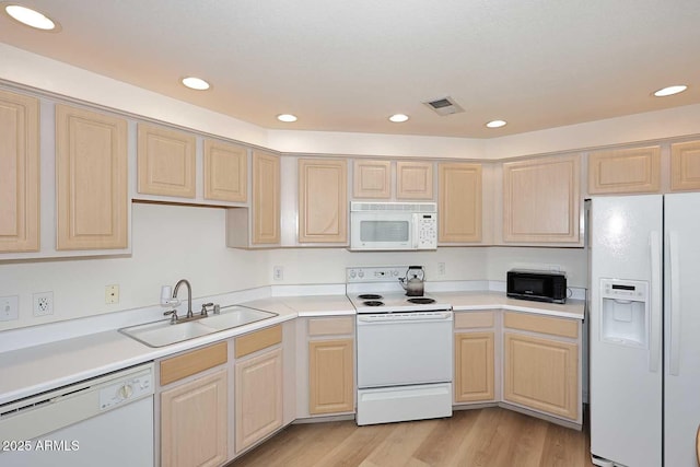 kitchen featuring white appliances, visible vents, light brown cabinetry, light wood-style floors, and a sink