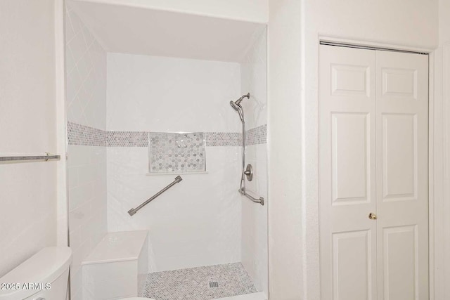 bathroom with toilet, a shower stall, and a closet