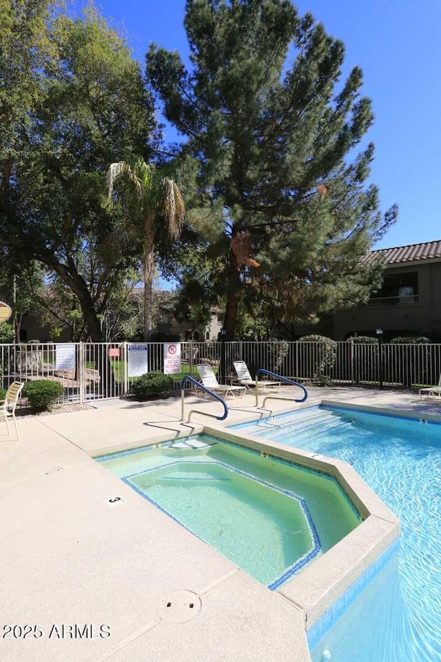 community pool with a patio area and fence